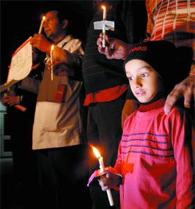 A child along with doctors from AIIMS holds candles during a peace march in New Delhi on Tuesday.