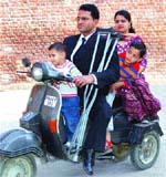 Riding High: Physically challenged Ashok Sharma with his wife and two sons on a scooter