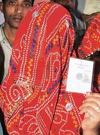 A voter shows her voter identity card as she waits for her turn to cast her ballot at a polling station, during the state assembly election, in Bikaner