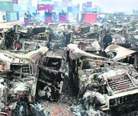 A security official stands among burnt military vehicles on the outskirts of Peshawar on Sunday. 