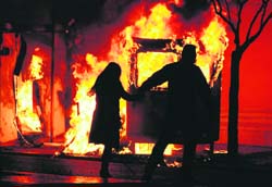 A couple runs to escape a fire from a bus-station booth during riots in Athens on Sunday.