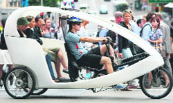 A pedal-power taxi with two women in the back moves through central Sydney on Monday.