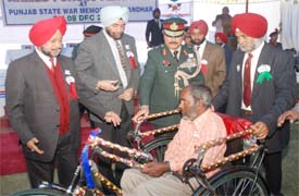 Lieut-Gen V.S. Tonk presents a tricycle to a physically challenged person