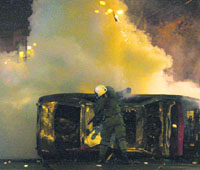 A policeman takes cover behind a burnt car during riots in Athens. 