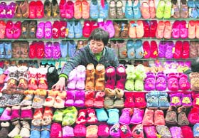 A vendor arranges footwear at her stall in a market in Nanjing, Jiangsu province