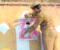 A policeman removes posters from a wall in Jammus BC Road area.