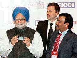 Prime Minister Manmohan Singh holds a newly launched 3G mobile phone as telecommunications minister A. Raja looks on at the "India Telecom 2008  Connecting Rural India" conference in New Delhi on Thursday.