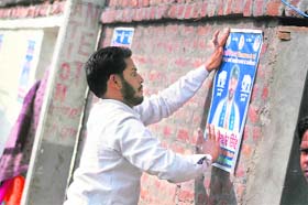 Despite the Municipal Corporation banning the defacement of public property, a party activist pastes posters on a wall