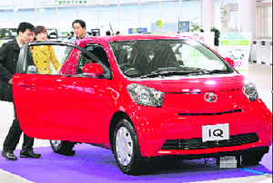Customers look at Toyota Motor's new compact car "IQ" at a Toyota showroom in Tokyo on Sunday.
