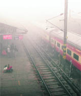 Passengers wait for a train amidst heavy fog at a railway station in Allahabad on Thursday.