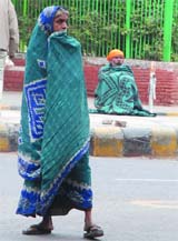 A gush of cool wind in New Delhi on Friday prompts people on the road to wrap themselves up in clothes. 