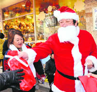 Japanese toymaker Yanomans president Seiichi Yano clad in Santa Claus costume hands out gifts to customers during a promotion of Christmas toy gifts at a Tokyo toy shop on Saturday.
