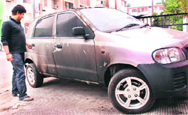 A man shows burnt Alto car in Sector 15 in Chandigarh on Saturday.