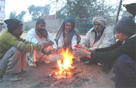 COLD COMFORT: People warm up on road in Gurgaon