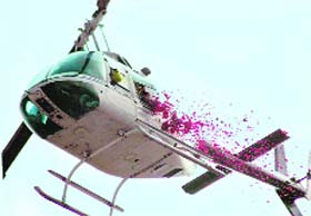 A helicopter showers petals on people assembled for an HJC rally in Rewari