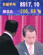 A man looks at a screen showing the Prime Minister of Japan in front of a securities company in Tokyo on Wednesday. Japanese share prices closed down 2.37 per cent on persistent worries about the auto sector after Toyota slashed forecasts and US carmakers shares skidded on Wall Street