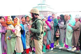 A CRPF jawan stands guard as women await their turn outside a polling station at Hazratbal in Srinagar district. 