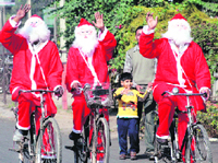 Three cyclists, dressed as Santa Claus, paddle on the streets of Ludhiana on Christmas eve.