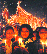 Youngsters hold candles outside a church on the occasion of Christmas in Jalandhar on Thursday.