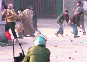 A CRPF jawan takes cover behind a shield as protesters attack him with stones and bricks during a protest in Srinagar