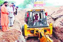 Minister for irrigation water Matabar Singh Kandari inspects the sewer laying work in Jwalapur while Swami Yatishwaranand looks on. 