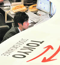 An employee of the Tokyo Stock Exchange monitors trading in Tokyo on Tuesday.