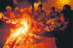 CHILL OUT: City residents gather around a bonfire to keep themselves warm, with region shivering from fog and chilly weather
