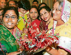Awami League president Sheikh Hasina (right) receives flowers from supporters at her residence in Dhaka on Tuesday.