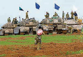 An Israeli soldier walks in front of armoured vehicles just outside the northern Gaza Strip on Tuesday.