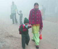 A child braves the thick early morning fog to go to school in New Delhi on Friday.