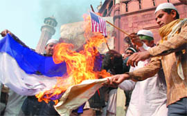 Muslims burn Israeli and American flags in front of Jama Masjid in New Delhi to protest Israeli military operations in Gaza, on Friday.