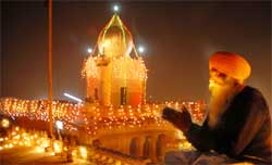 A devotee offering prayers at the illuminated Qila Mubarak gurdwara in Bathinda