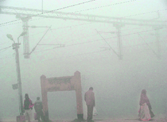 People wait at a fog-engulfed railway platform in Faridabad on Saturday.