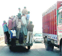 People cling to a minibus in Samba where the overloading of passenger vehicles is a common sight.
