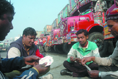 Truck drivers and helpers play cards on the second day of their strike at Azadpur in Delhi on Tuesday.