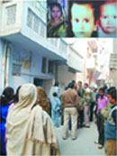 People gather outside the house of Hemchand whose wife and two sons (inset) were found murdered in New Delhi