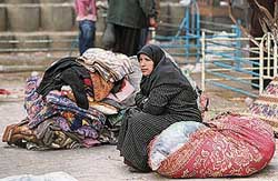 A Palestinian woman, who fled her house during Israels offensive, sits beside her belongings outside a UN-run school in Beit Lahiya in the northern Gaza Strip