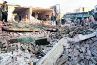 Residents stand on the rubble of a damaged government school, wrecked by Islamic militants in Mingora, main town of Pakistans Swat Valley, on Monday.