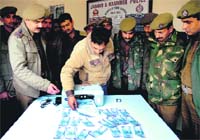 Accused Rajeev Sharma uses a printer to churn out a fake Rs 100 currency note in Jammu on Sunday.
