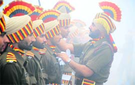 A jawan arranges the dress of a fellow ahead of Republic Day parade in Ludhiana on Monday.