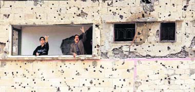 Palestinians gesture from a damaged house near the border of Gaza and Egypt in the southern Gaza Strip