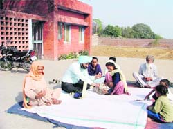 A doctor examines patients while squatting on the floor at a rural dispensary in Jaspal Bangar village, Ludhiana, on Thursday.