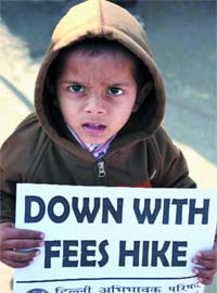 A child holds a placard during a protest against the school fee hike at Rajghat in New Delhi