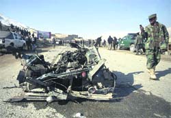 An Afghan soldier takes a picture of the wreckage of a vehicle used by a 