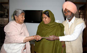Raghubir Kaur Mokha giving away a financial aid to Kaur Singh, who is handicapped, and his blind wife in Bathinda on Wednesday.