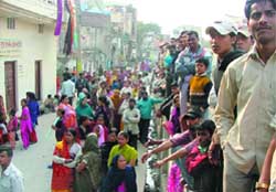 People gather outside the house where a mans body was found while his wife went absconding, at Khazuri Khas in East Delhi 