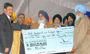 Chief Minister Parkash Singh Badal hands over a cheque at Dana Mandi in Nawanshahr on Thursday.