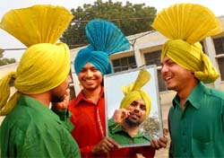 A turbaned youth studies himself in a mirror.