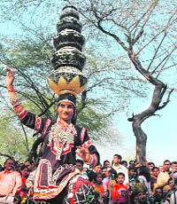A woman folk artiste balances five earthen pitchers on her head while presenting a dance item at the Surajkund Crafts Mela in Faridabad on Sunday.