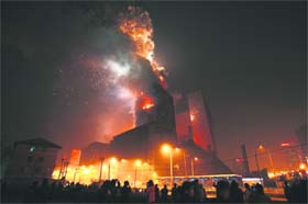 Crowd watch as the building that housed the to-be-opened Mandarin Oriental Hotel explodes after it caught fire in Beijing